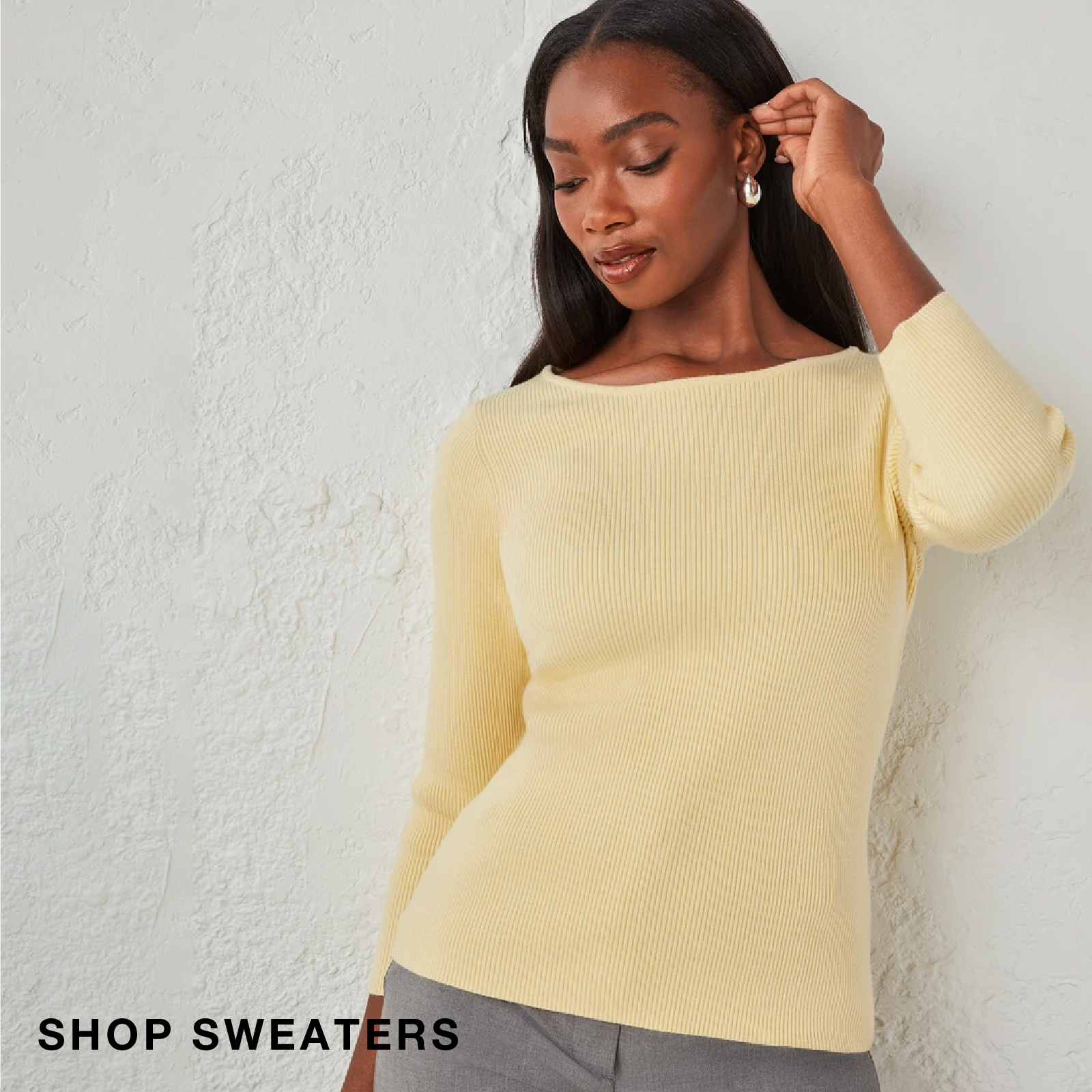 Woman wearing a yellow sweater, posing against a textured background.