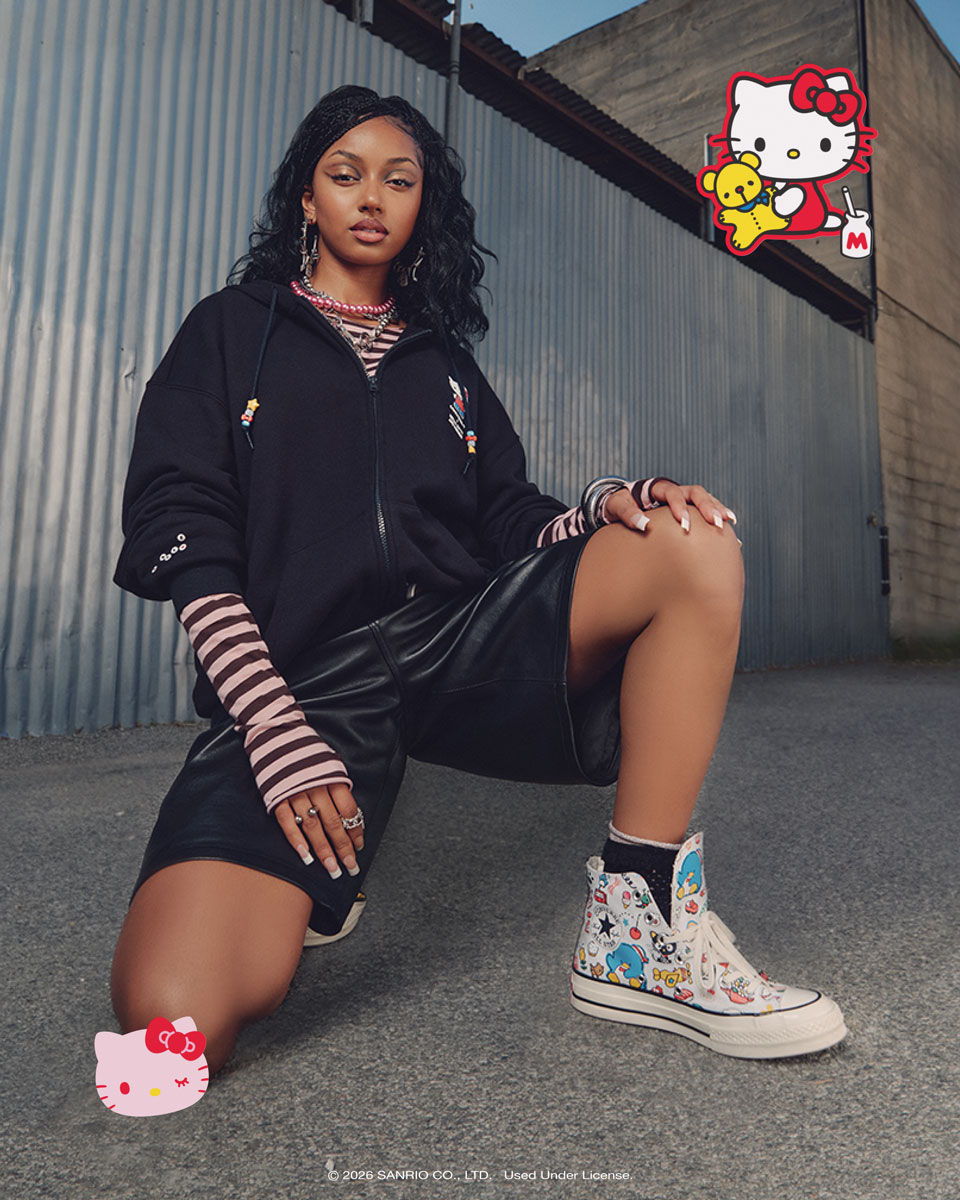 Person posing in stylish outfit with Hello Kitty graphics in the background.
