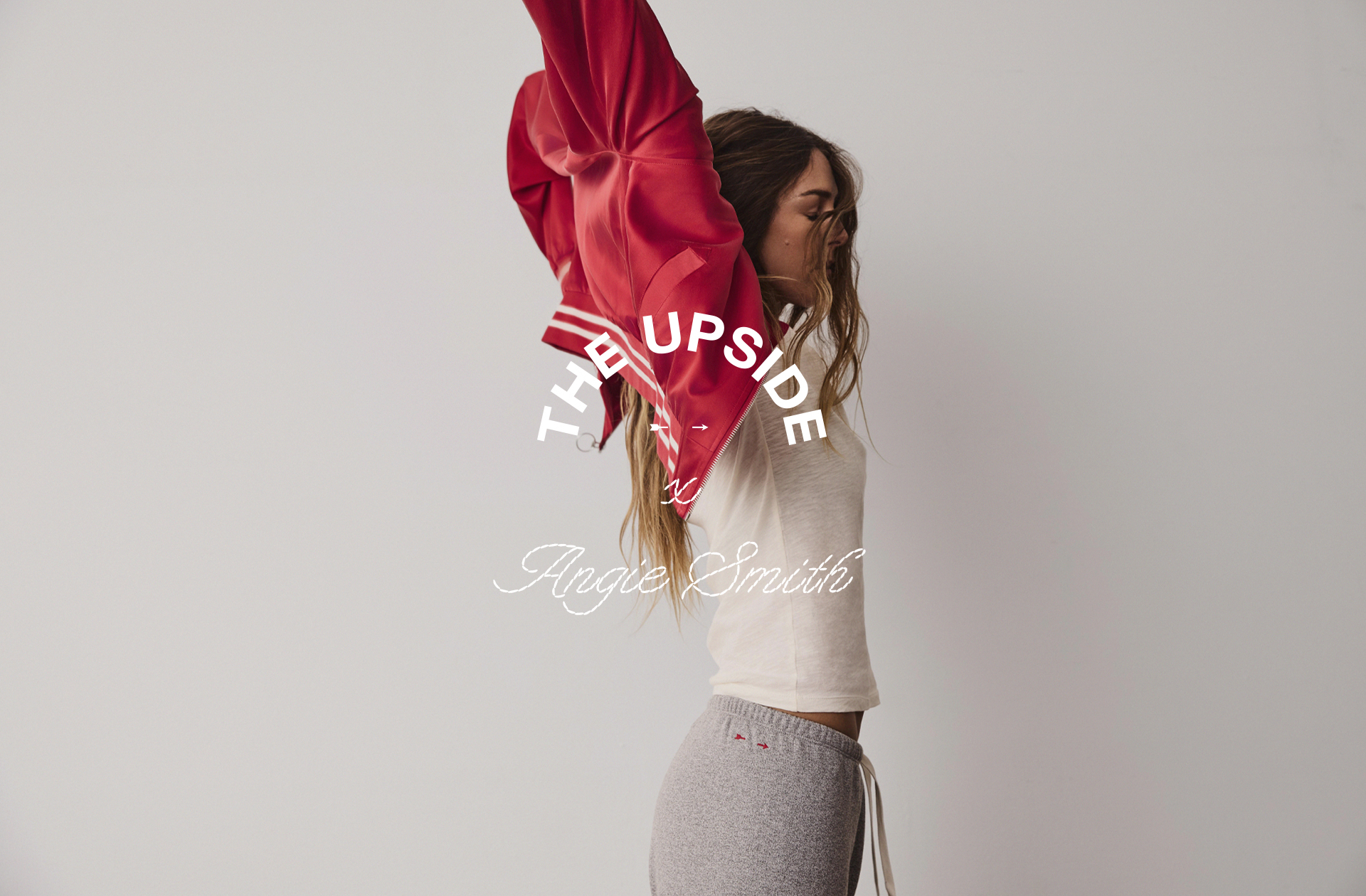 Woman raising a red jacket against a light background.