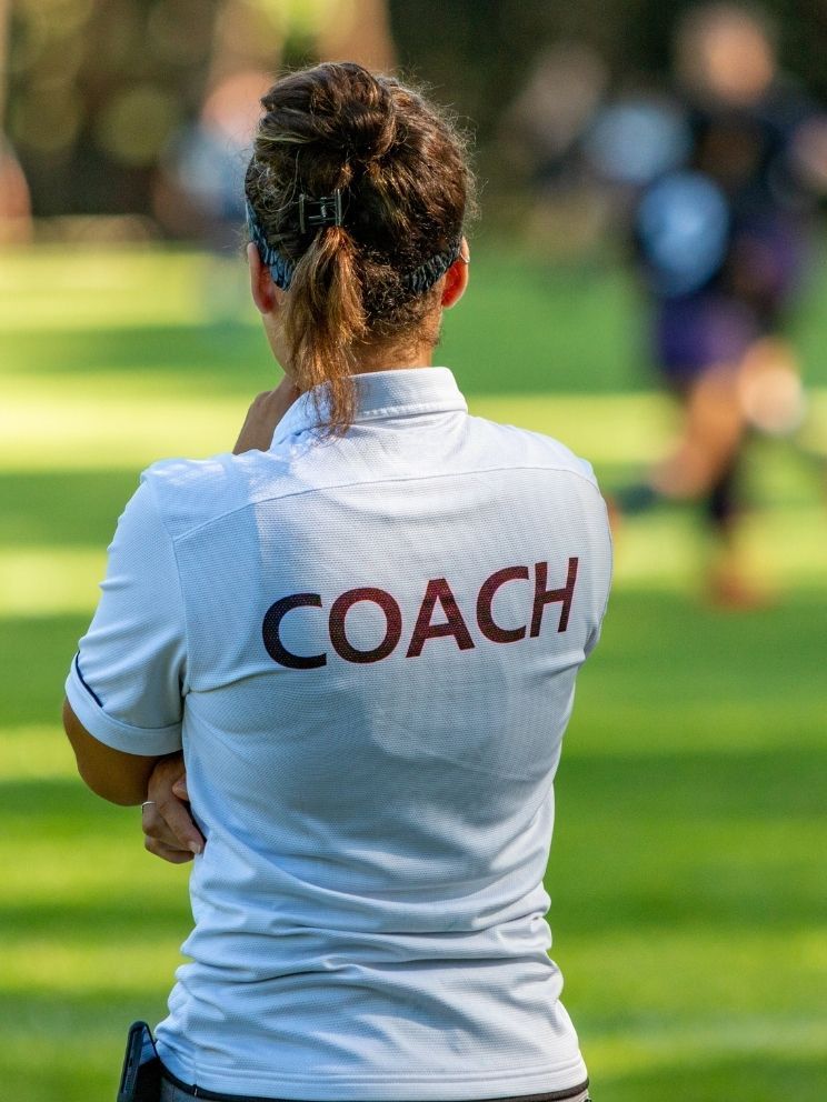 School coach watching training session on sports field