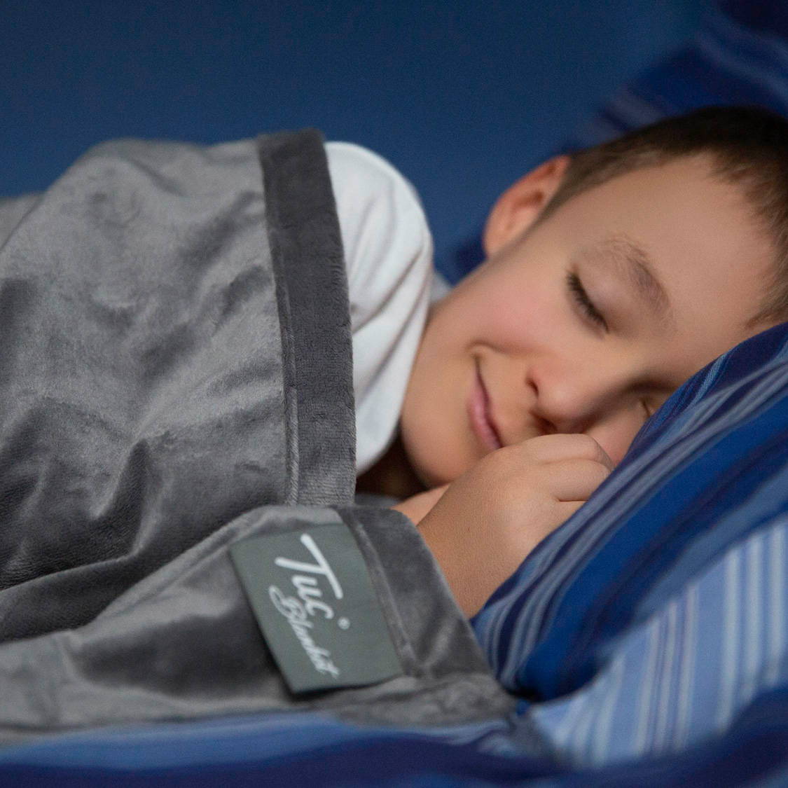 Boy rests peacefully with a Tuc Blanket and a smile. 