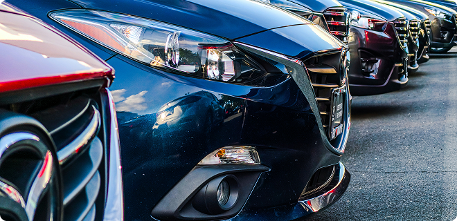 Close-up of parked cars, showcasing their front designs and colors.
