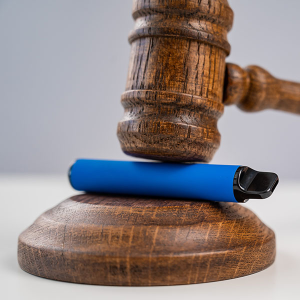 A photo of a gavel sitting on top of a disposable vape 