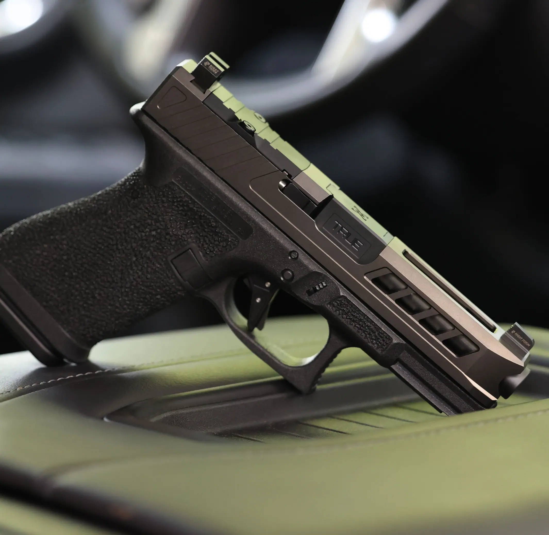 Glock 19 with grey True Precision slide and barrel, sitting in the center console of a car.