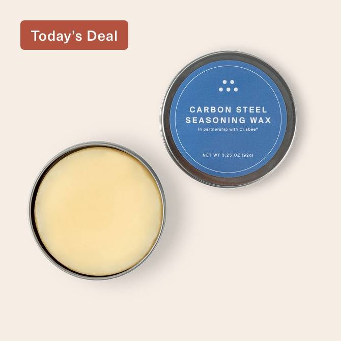 An open tin of Misen Carbon Steel Seasoning Wax seen from above, with beige wax and blue-and-white lid label visible.