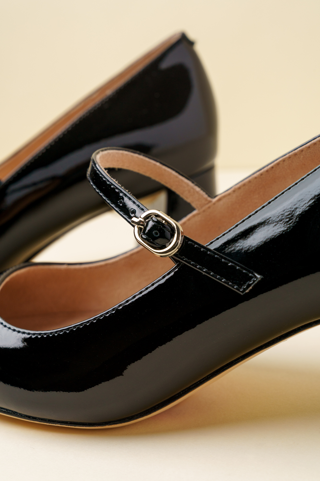 A pair of black patent leather high-heeled shoes with ankle straps.
