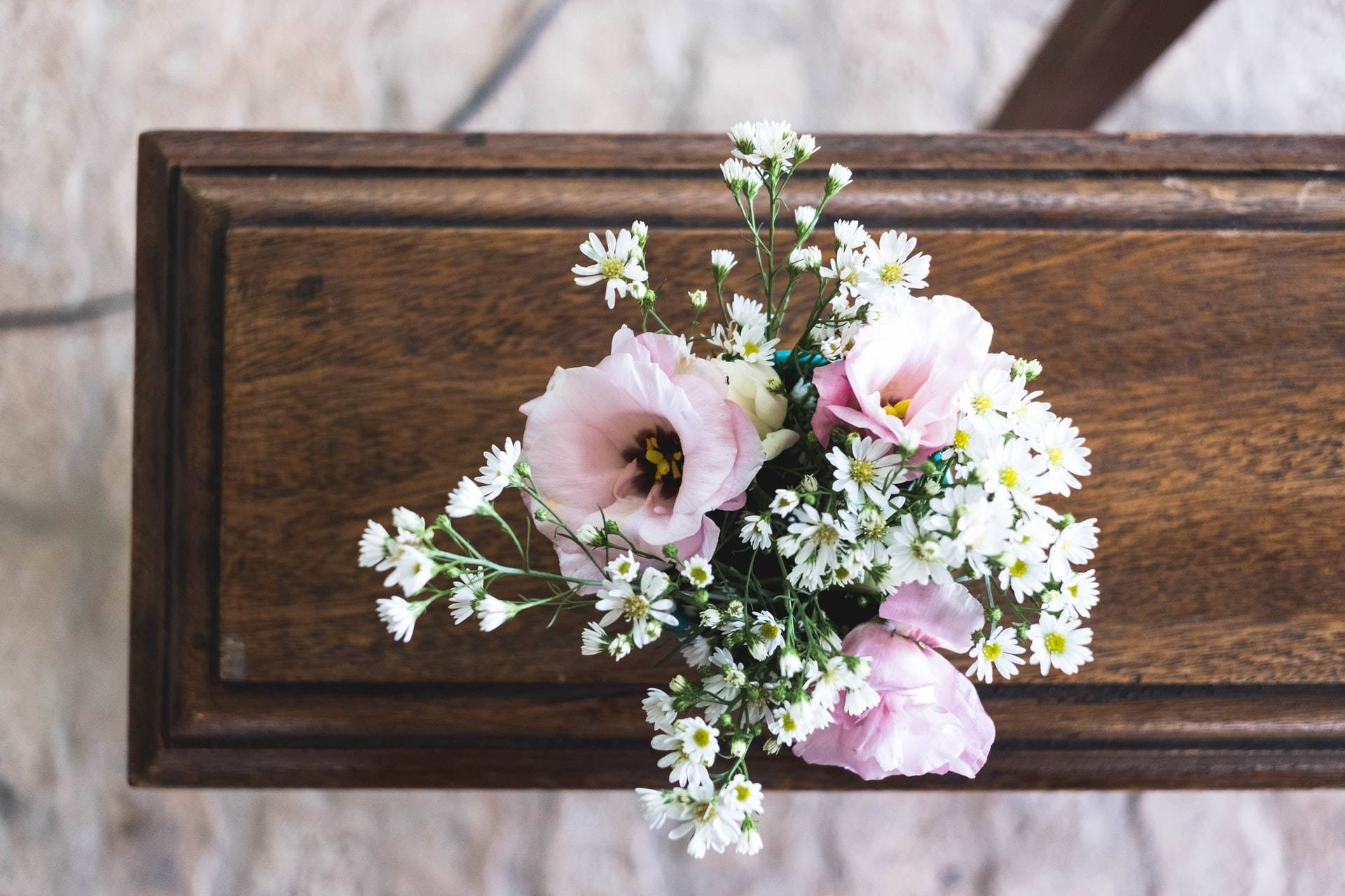 A closed casket with pink and white flowers resting on it during a funeral