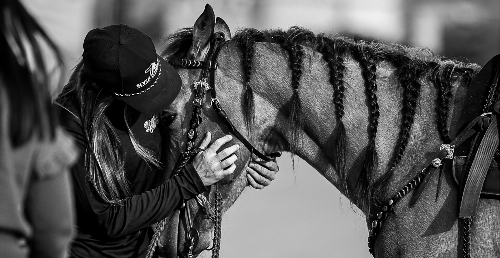 Person kissing a horse in black and white setting.