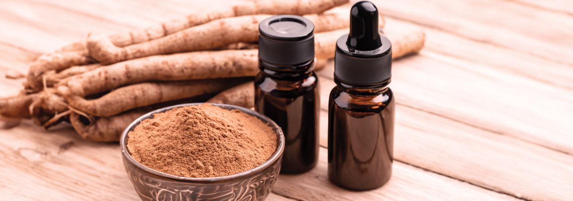 Bottles of herbal oil and powdered root on a wooden surface.