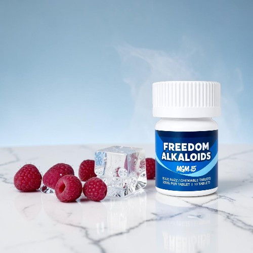 Bottle of Freedom Alkaloids with raspberries and ice cubes on a marble surface.