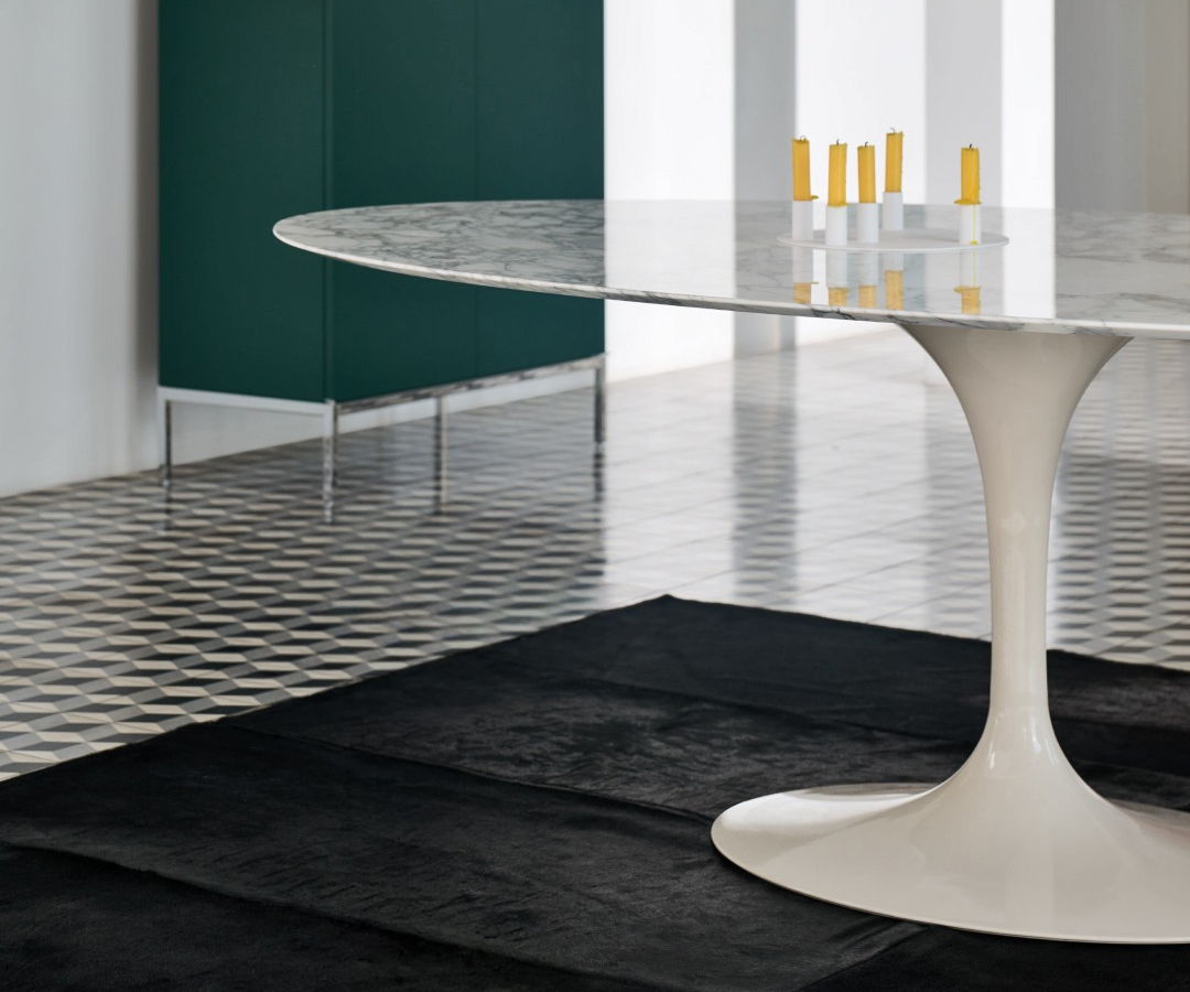 Modern cream Saarinen chair with a pink cushion beside a marble table.