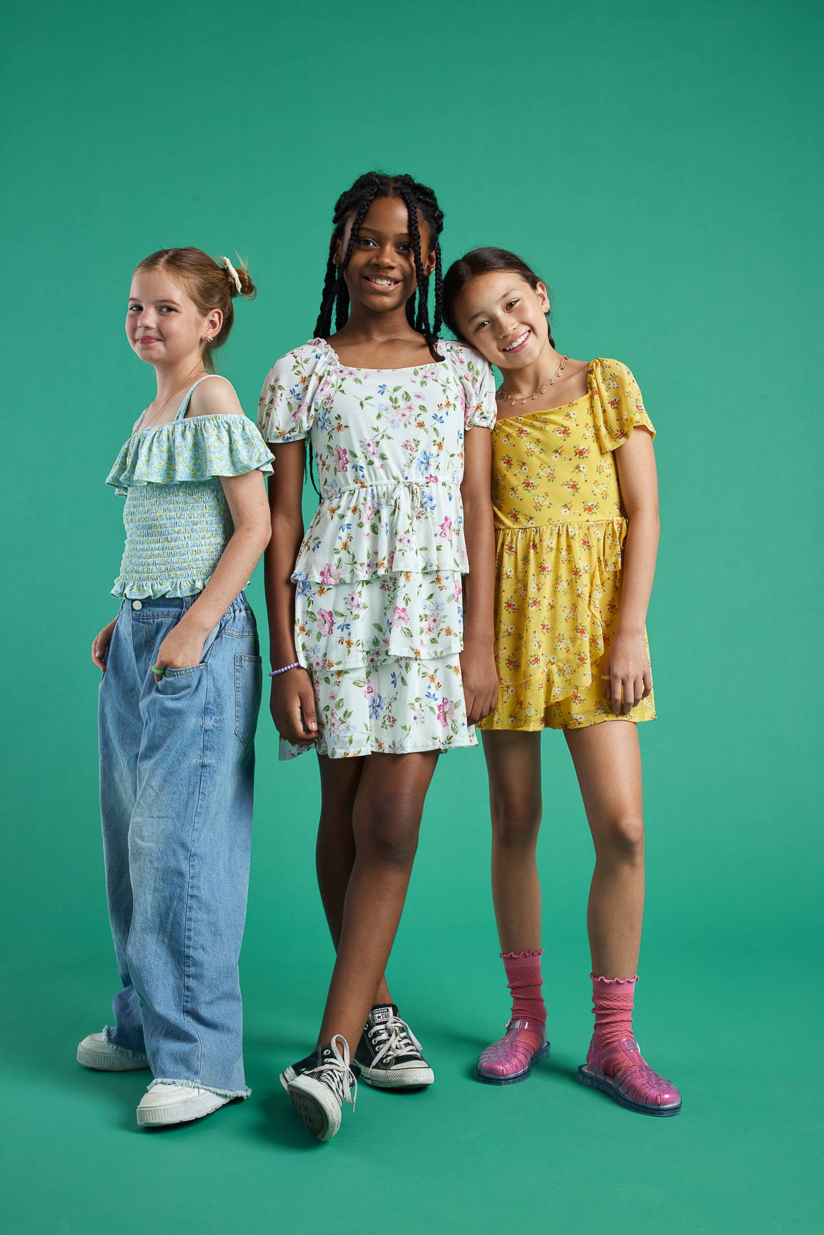 Trixxi girl kids shop all, 3 young girls in a trixxi teal floral ruffle top, white floral romper, and yellow floral romper. 