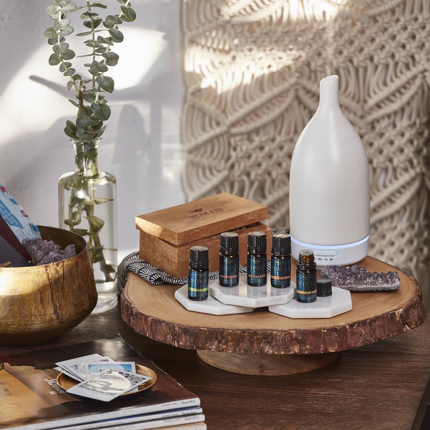 A white ultrasonic diffuser with a collection of diffuser oils in a living room setting