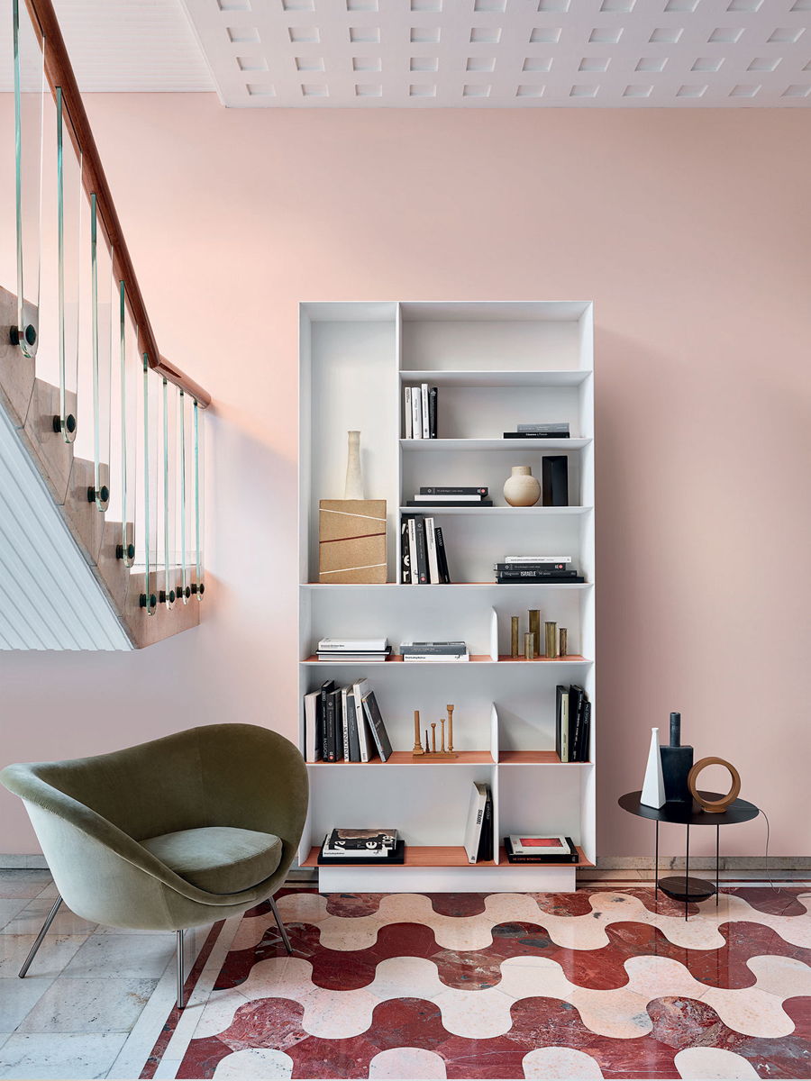 A modern room with a bookshelf, chair, and patterned rug.
