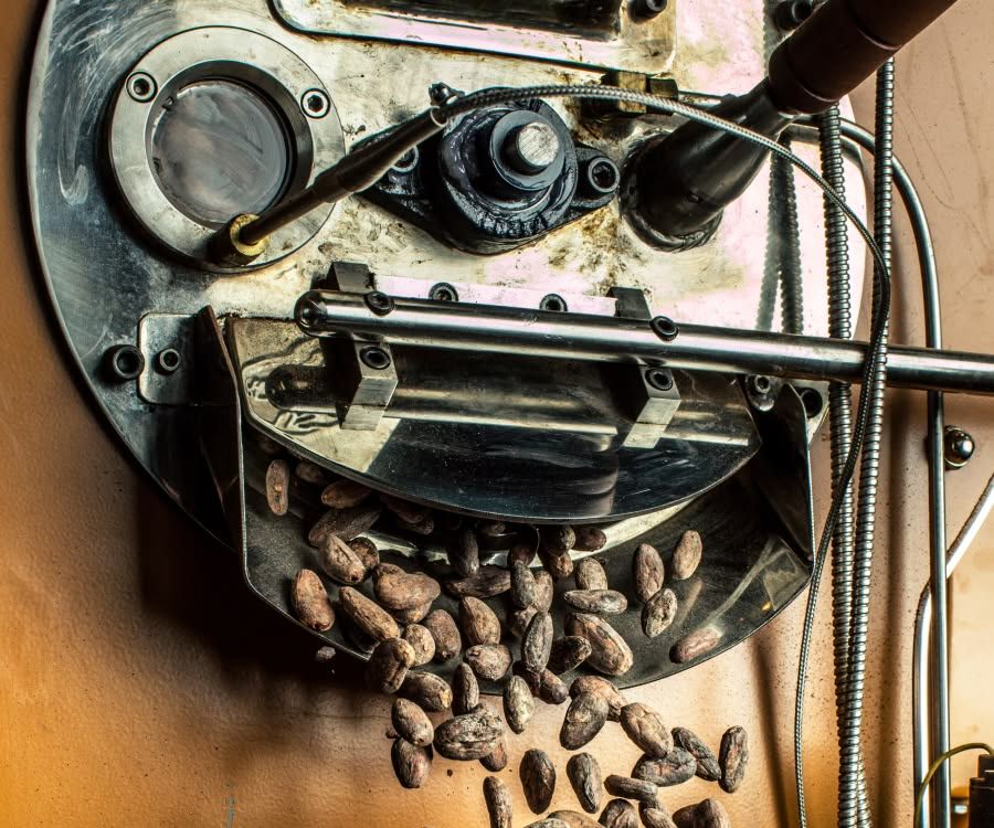 Close-up of a coffee roasting machine with beans falling out.