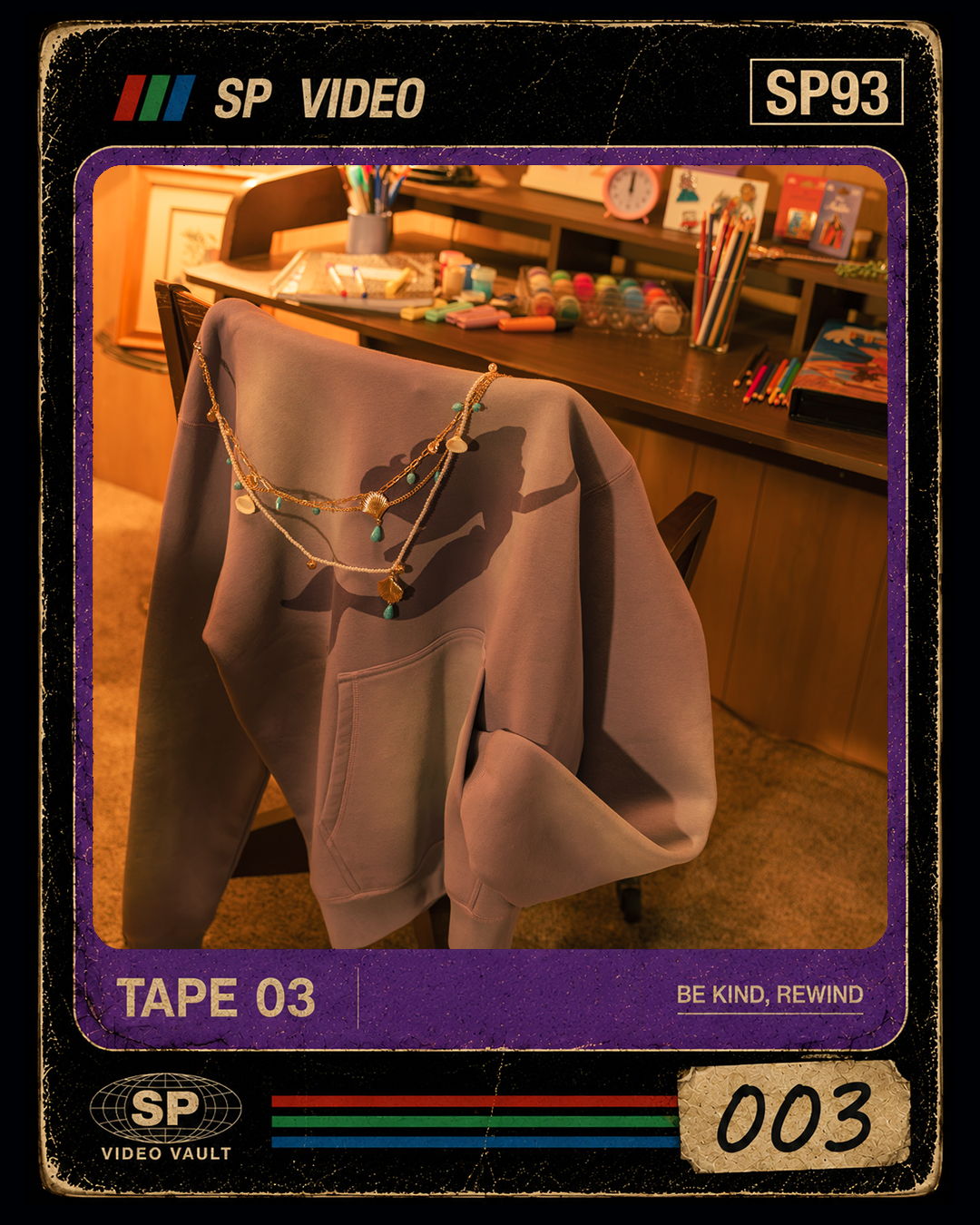 A purple sweatshirt hanging on a chair near a desk with art supplies.