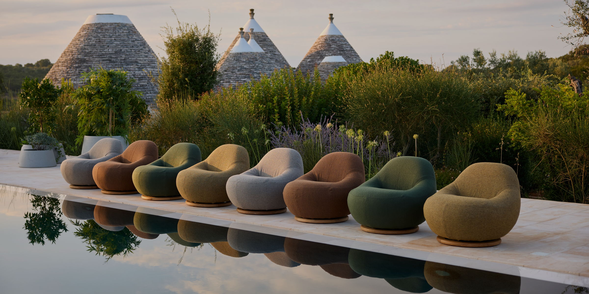 Plush modern rounded chairs in a line along the edge of a pool.