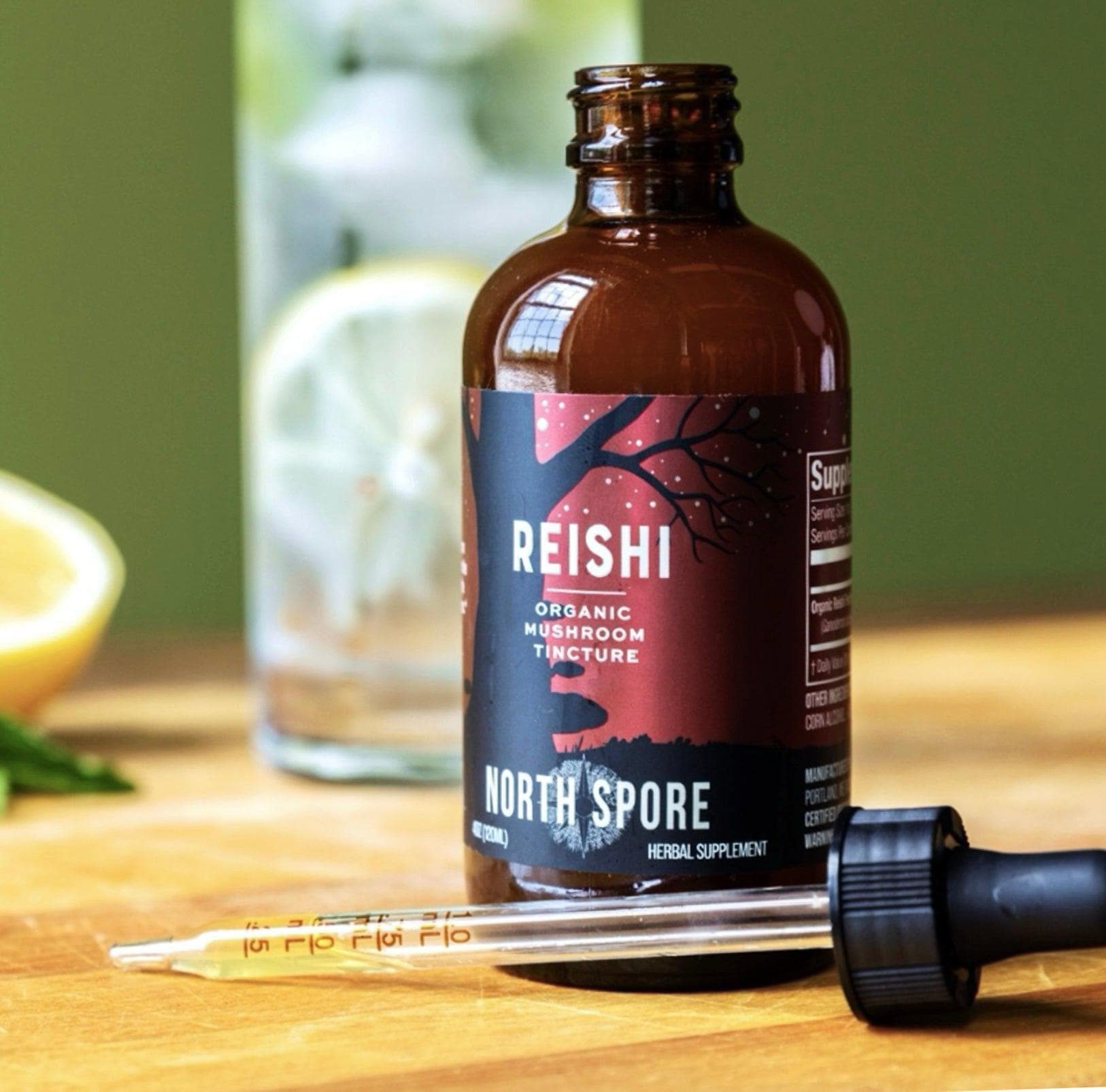 Reishi mushroom extract bottle on a wooden surface with a drink in background.