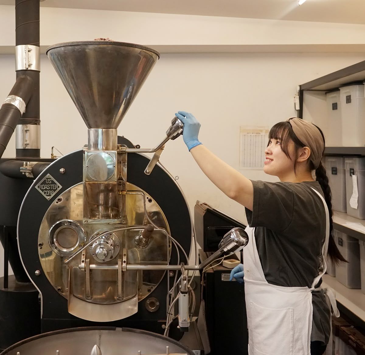 Person operating a coffee roasting machine in a cafe setting.