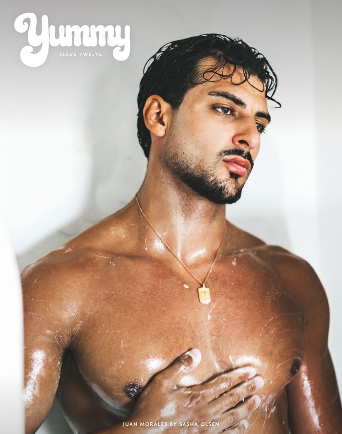 A man with wet hair, standing shirtless in a shower.