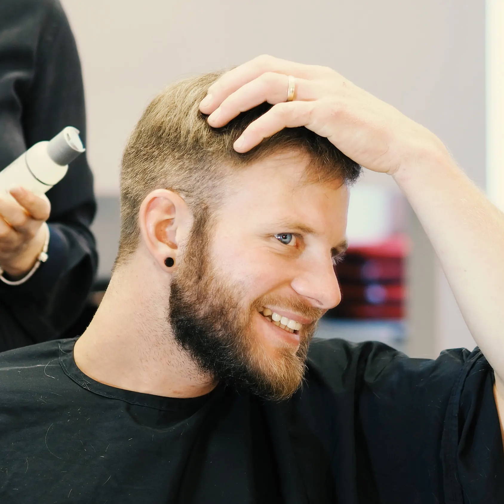 Mann stylt sein Haarsystem im Zweithaarstudio