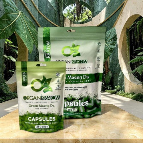 Two packages of green capsules on a marble table surrounded by foliage.