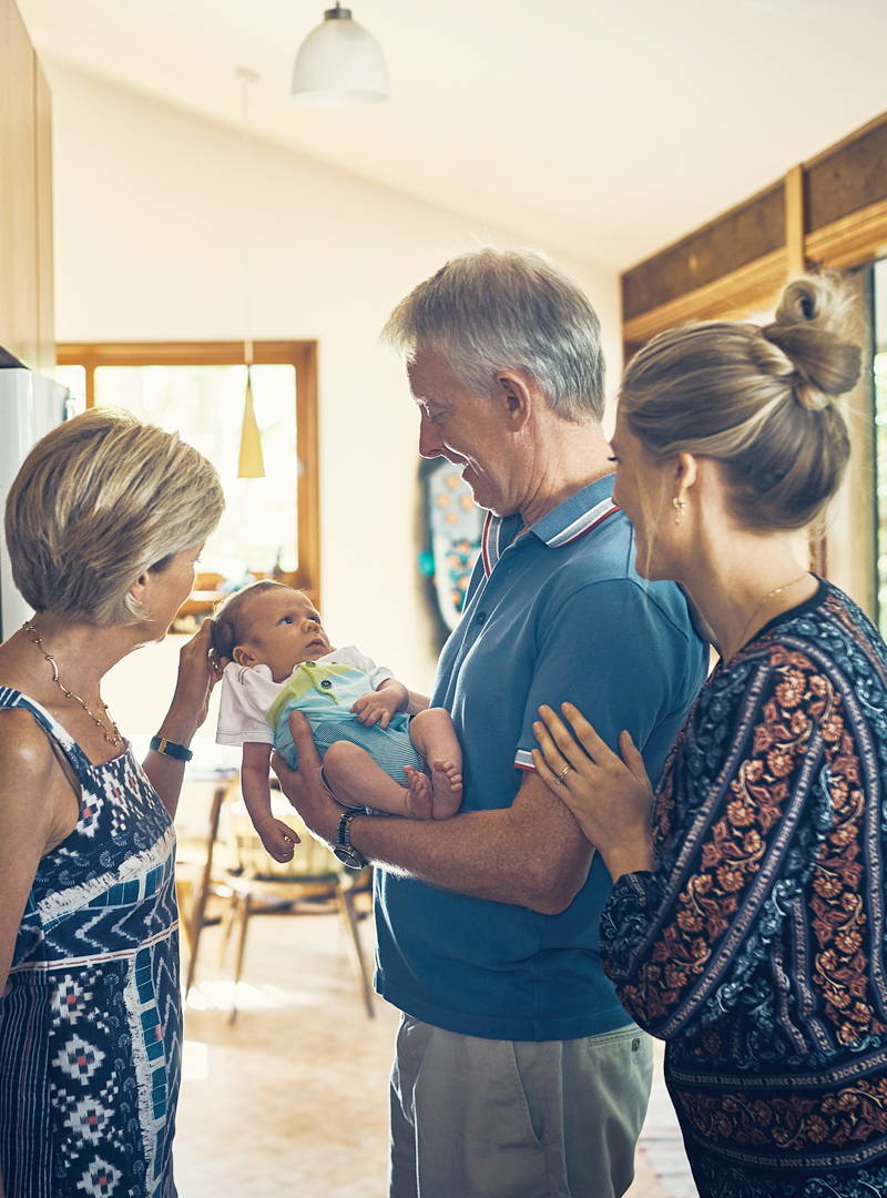 Grandfather with Alzheimer's Disease and Dementia happy after receiving a Dawn Clock. He is holding grandson with wife and daughter. 