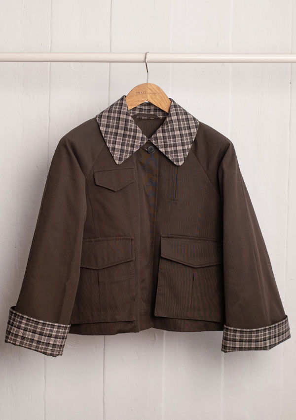 Brown jacket with plaid collar and cuffs hanging on a wooden hanger.