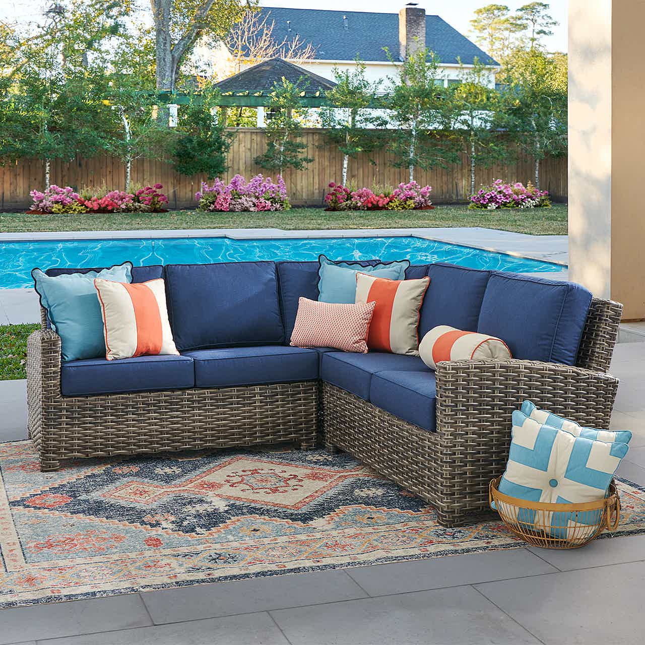 Outdoor sectional sofa with colorful cushions by a poolside.