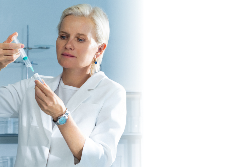 A woman in a lab coat preparing a syringe in a laboratory setting.