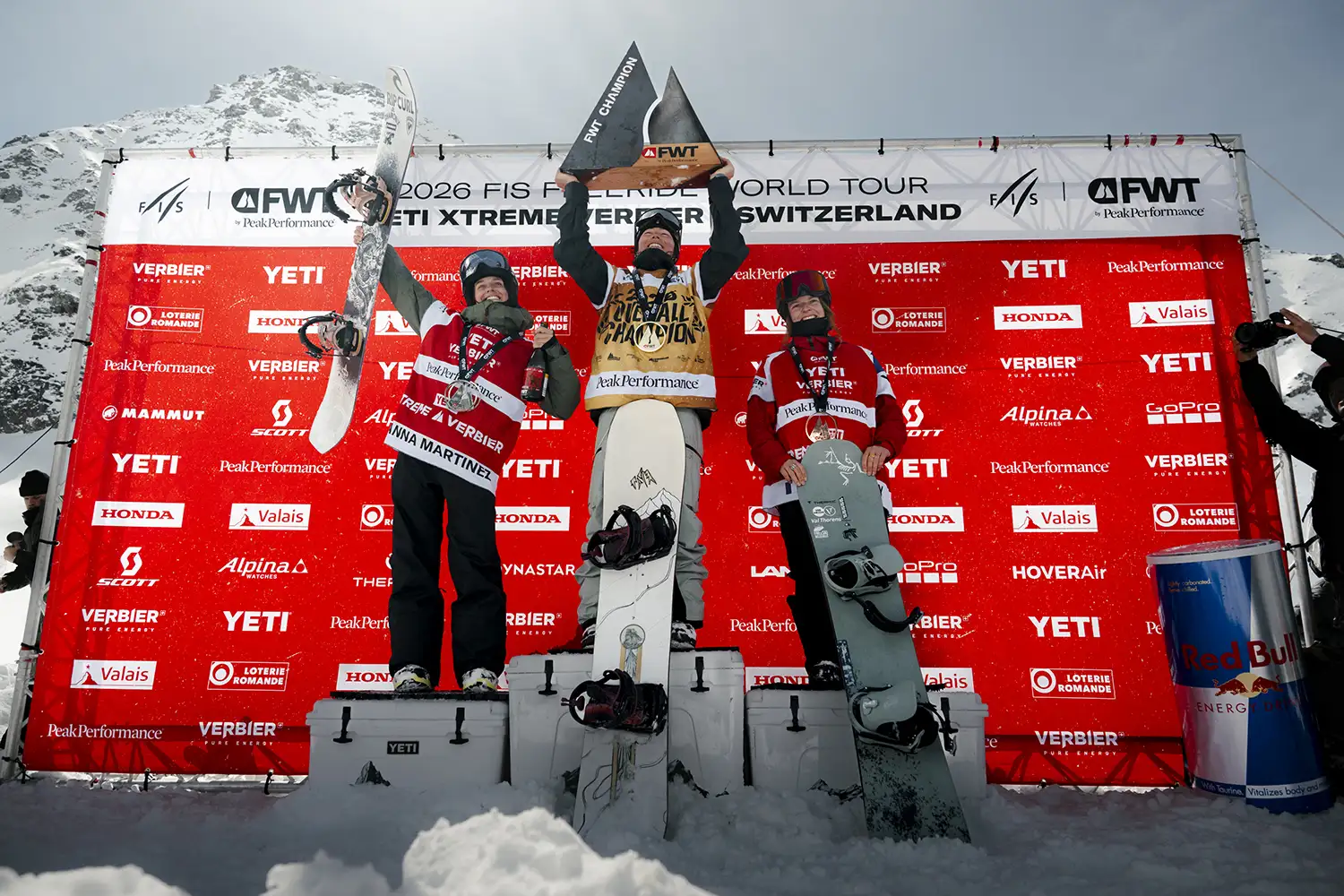 Three snowboarders on a podium celebrating at a competition in Switzerland.