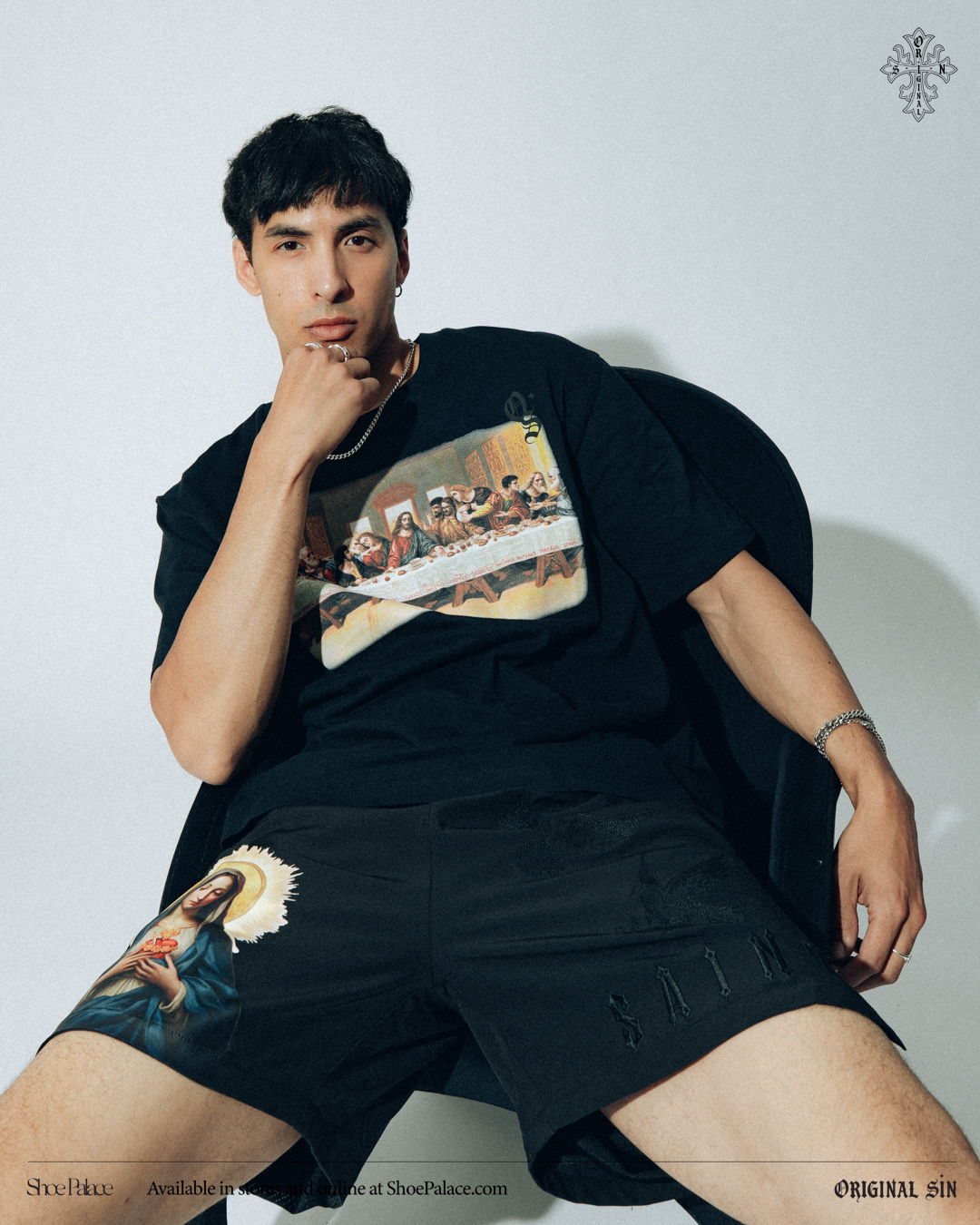 Young man in graphic t-shirt and shorts, posing in a stylish manner.