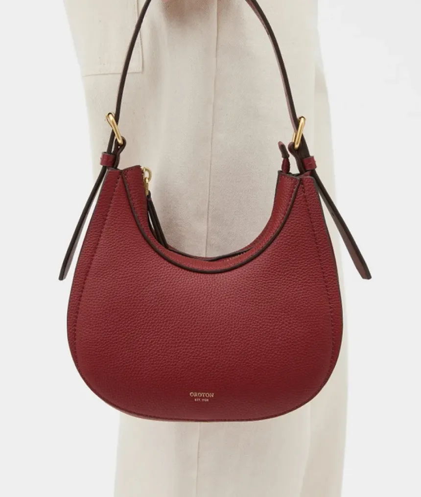 A red leather handbag with a curved shape and shoulder strap.