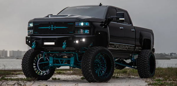 Front three-quarter view of Brandon's black lifted 2018 Chevrolet Silverado 2500 with teal suspension and large custom wheels, Katrina 544K train horn install photo 1