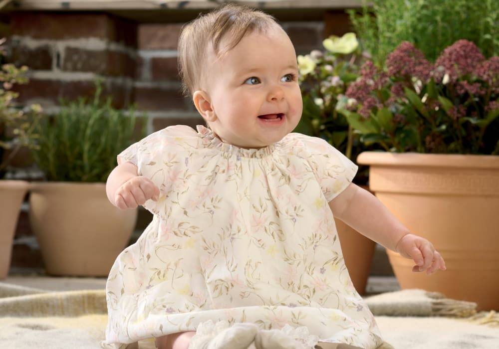 Smiling baby wearing a floral dress