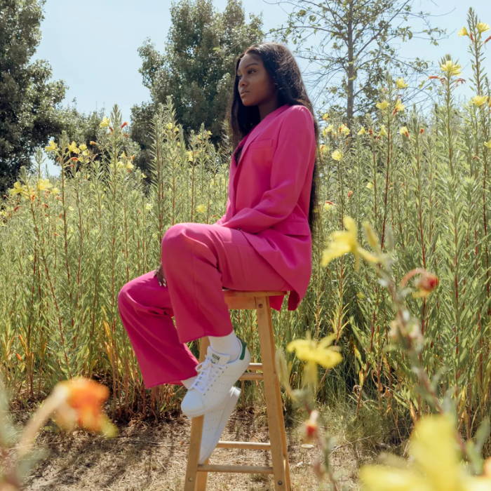female model in pink suit wearing white adidas stan smith in flower field