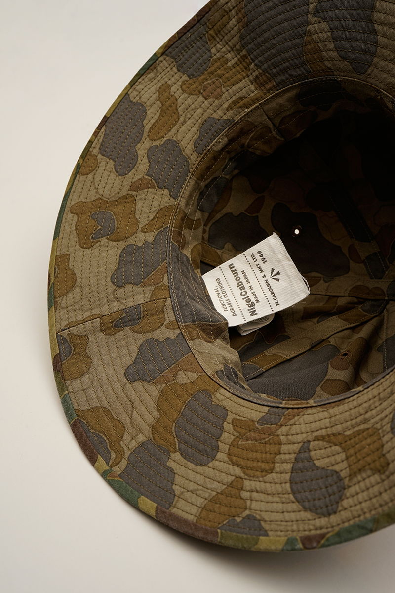 Interior view of a camouflage hat with a care label inside.