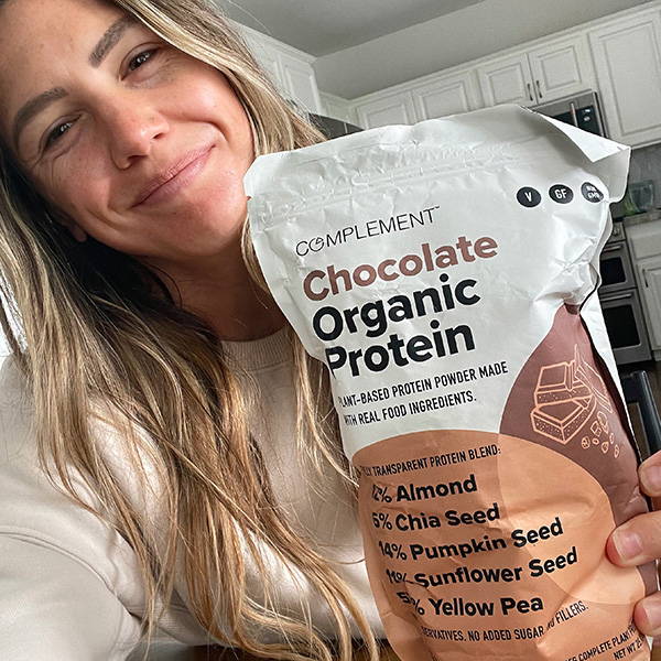 Woman smilling with a bag of chocolate organic protein
