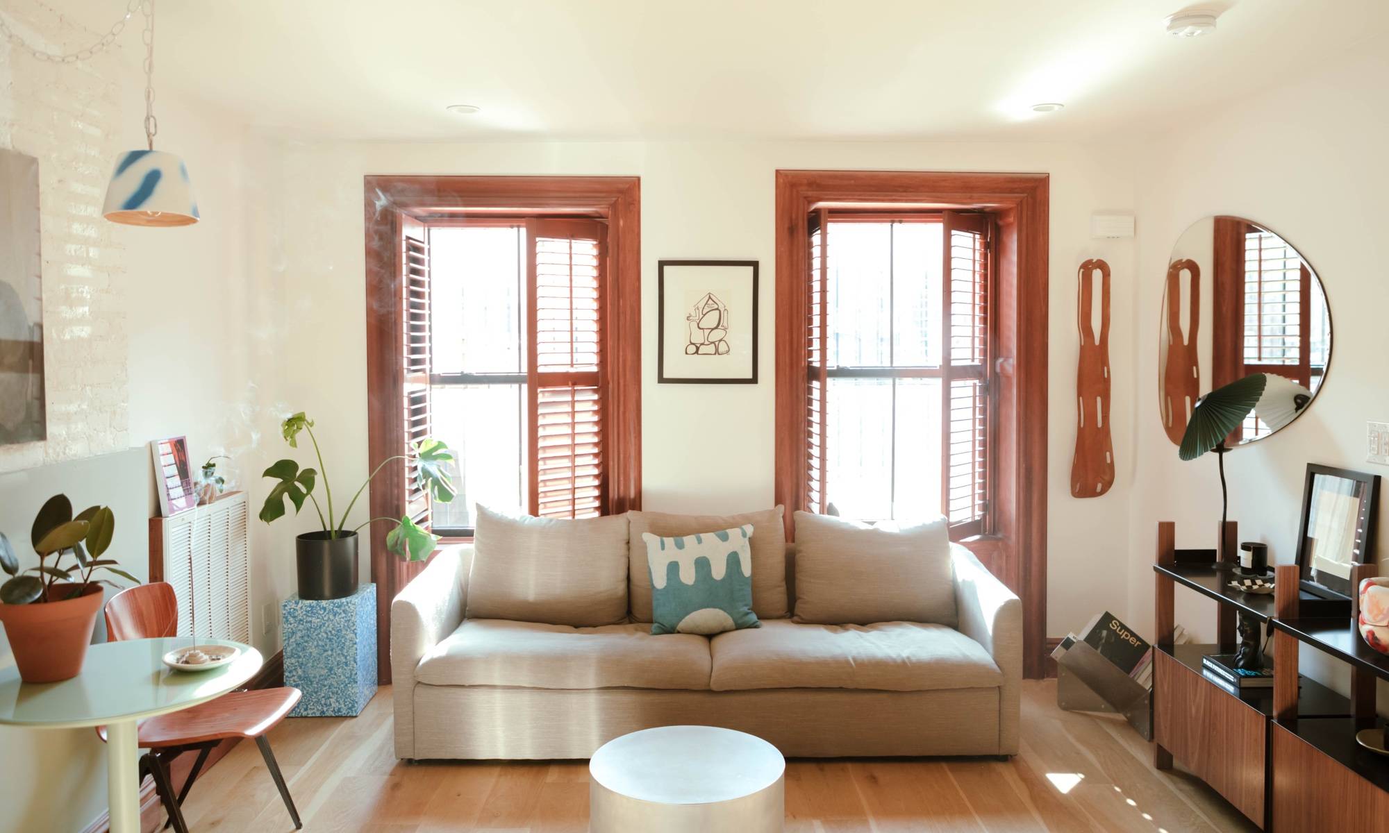 Bright living room in renovated brownstone with modern tan couch, table and shelves