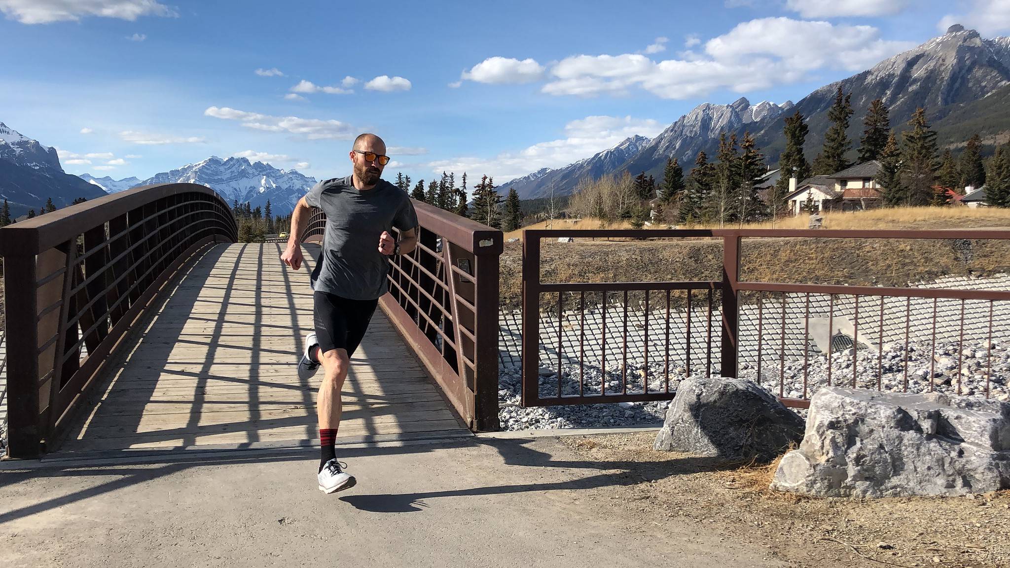 Man running across a bridge with a scenic backdrop of mountains.