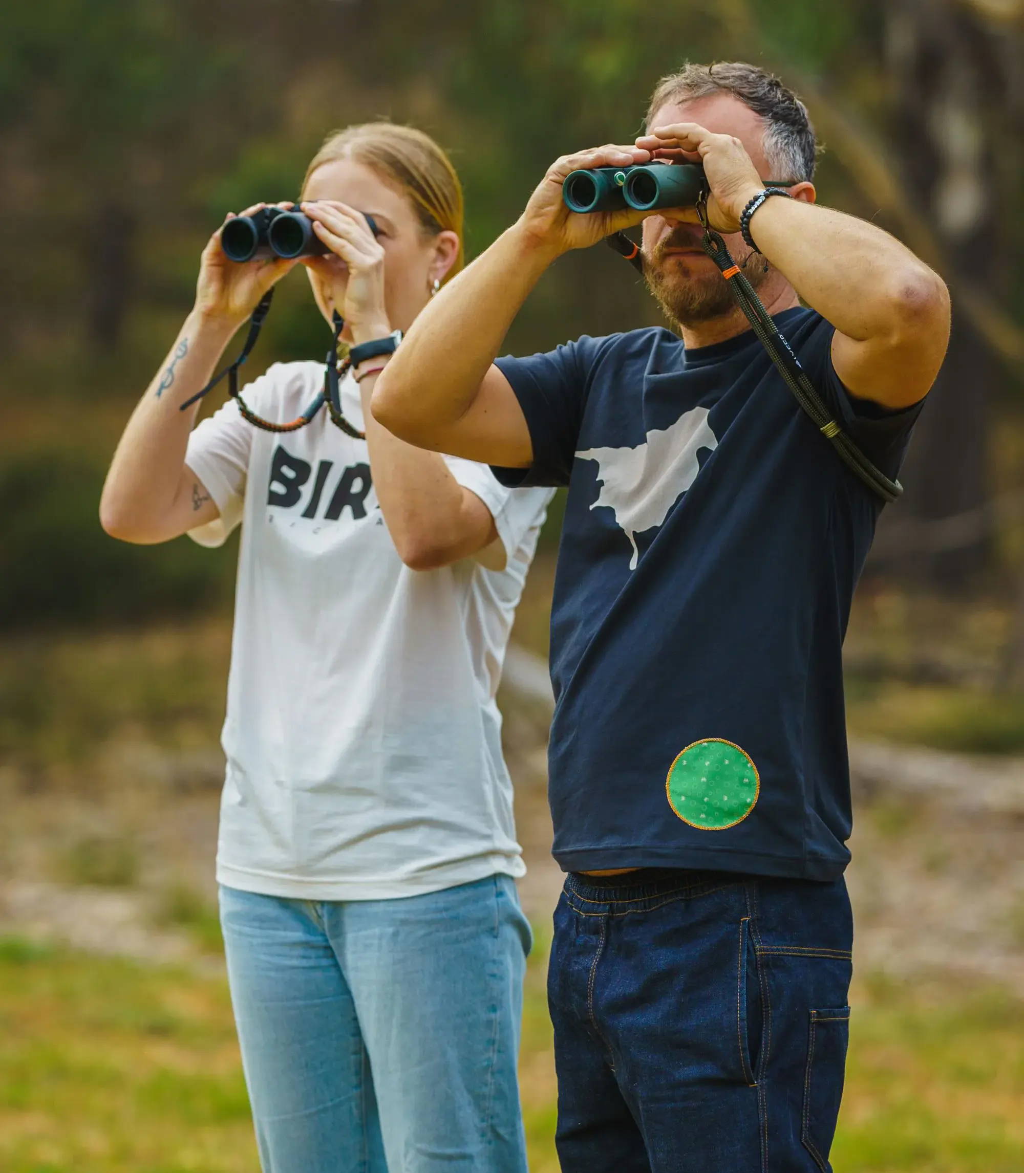 Male and Female bird-watching looking through binoculars in nature