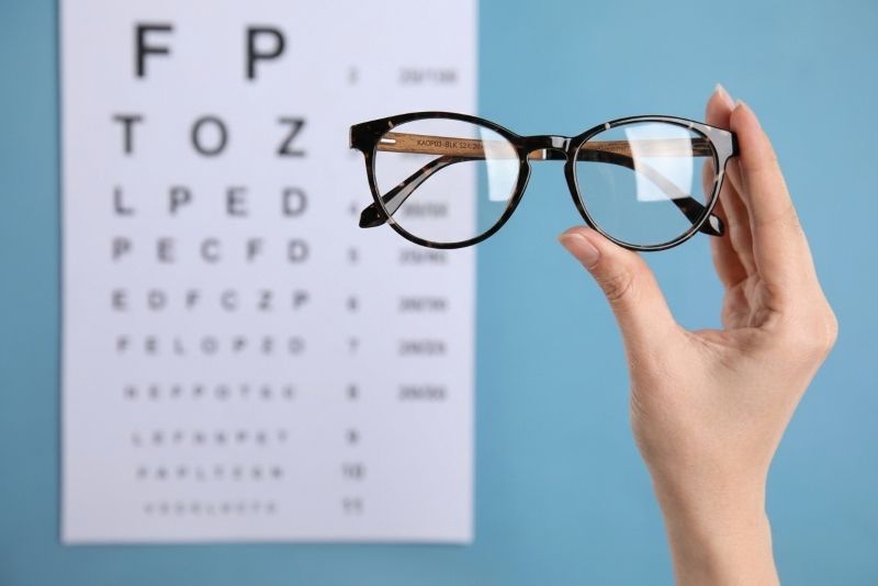 Hope Black eyeglasses held in front of eyeglasses reading chart
