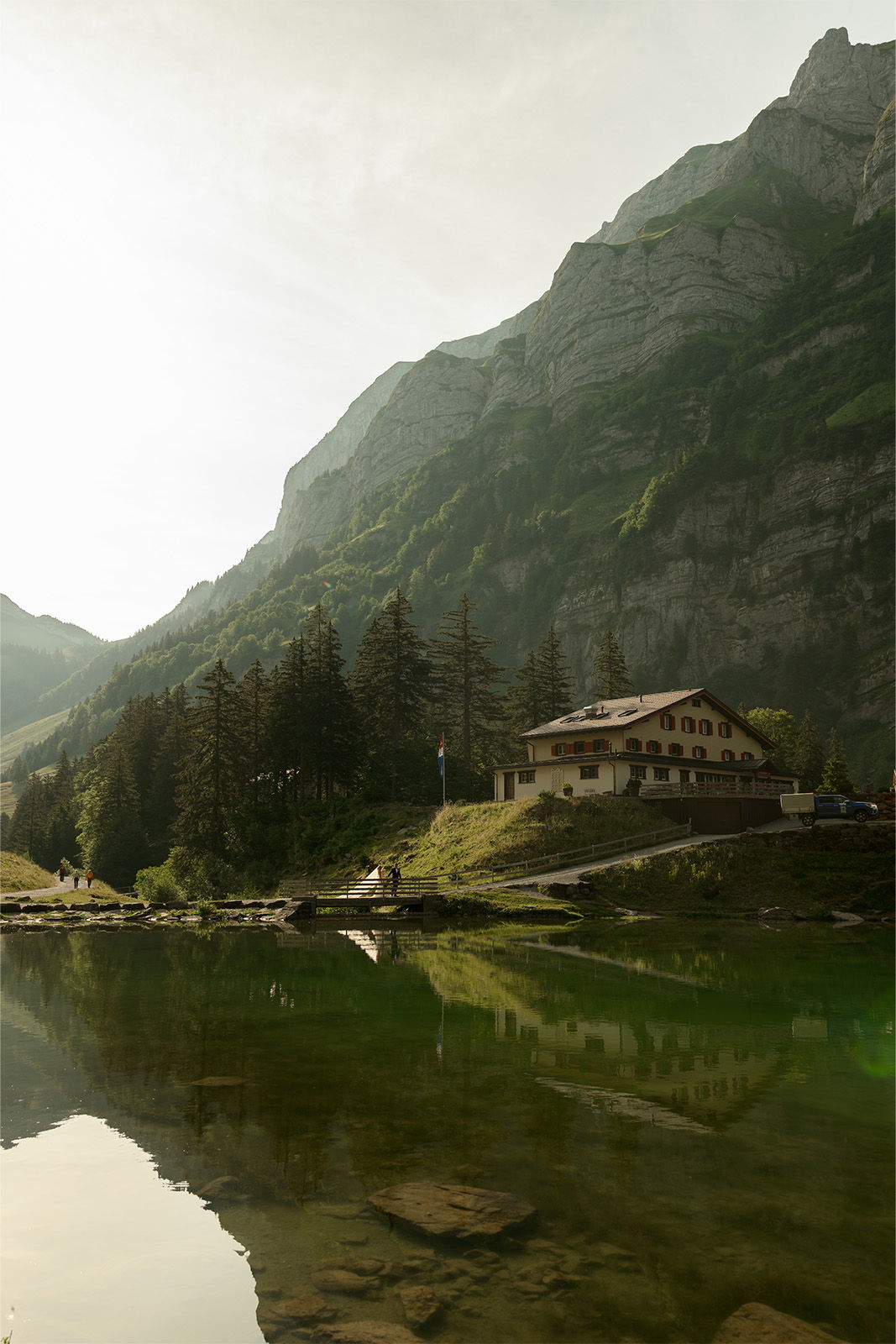 Scenic mountain landscape with a lake and a rustic house.