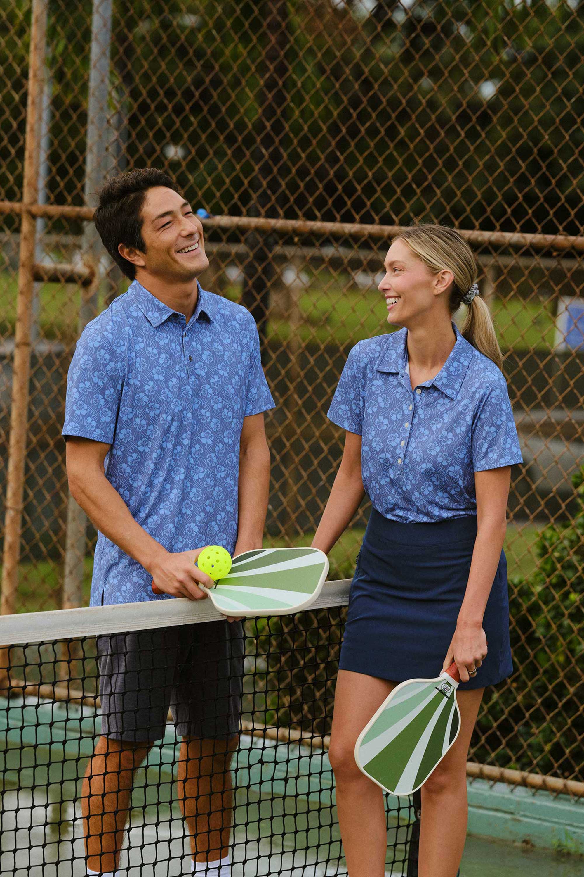 Two people smiling and holding paddles on a sports court.