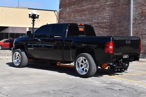 Rear three-quarter view of Lucas's black 2008 Chevrolet Silverado 2500HD parked downtown with polished wheels, install photo 3