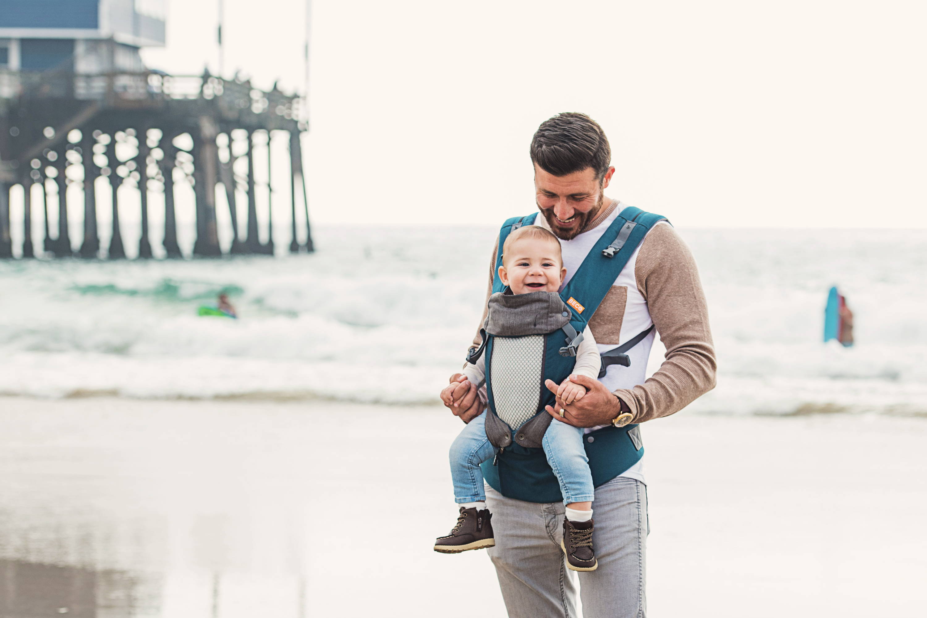 Dad carrying toddler front facing at beach in Beco 8 baby carrier