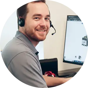 Smiling man wearing a headset, working at a computer.