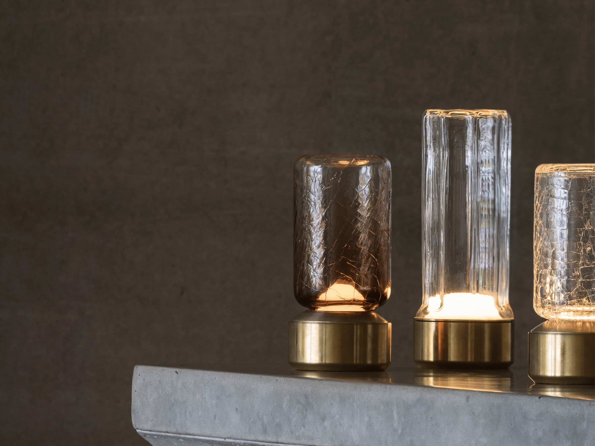 Three decorative glass lamps on a stone surface against a dark background.