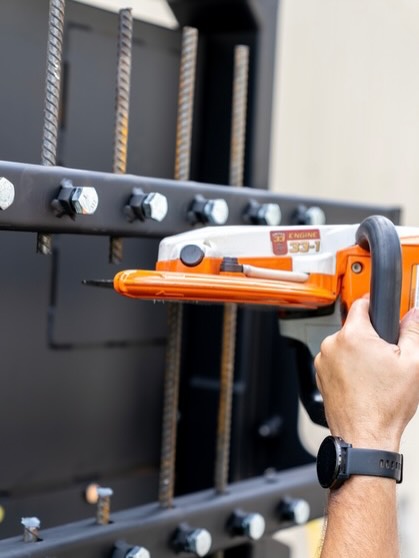 A person using a handheld tool on a metal structure.