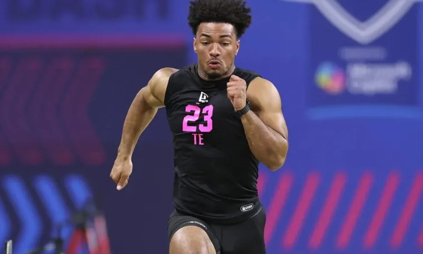 Athlete sprinting during a sports event, wearing a black jersey with the number 23.